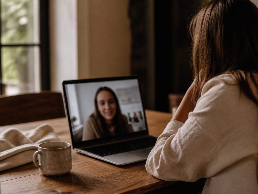 A person on a video call at a wooden table in warm natural light