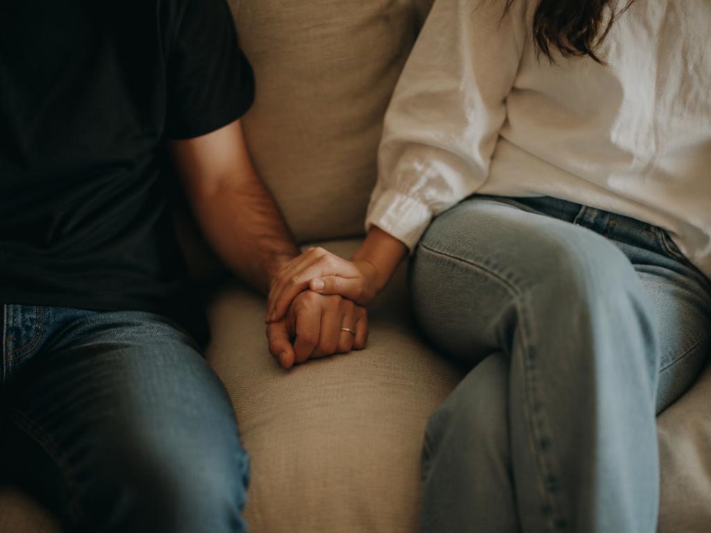 A couple sitting side by side, holding hands